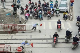 Trên đường Giải Phóng, mặc dù có rào chắn cẩn thận nhưng khi tàu chuẩn bị chạy qua, nhiều người dân vẫn bất chấp tính mạng vượt qua. (Ảnh: Minh Sơn/Vietnam+)