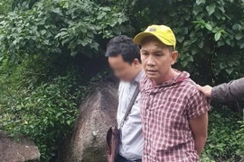 Nghi phạm Lê Trường Thành (áo kẻ) bị bắt giữ. (Ảnh: TTXVN phát)