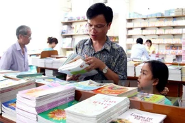 Phụ huynh và học sinh lựa chọn sách giáo khoa. (Ảnh: TTXVN)