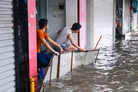 Nhiều cửa hàng trên phố Phạm Ngọc Thạch đã dùng cả biển quảng cáo để chống nước ngập vào nhà sau cơn mưa lớn sáng nay 13/6. (Ảnh: Minh Sơn/Vietnam+)