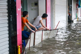 Nhiều cửa hàng trên phố Phạm Ngọc Thạch đã dùng cả biển quảng cáo để chống nước ngập vào nhà sau cơn mưa lớn sáng nay 13/6. (Ảnh: Minh Sơn/Vietnam+)
