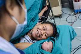 Khoảnh khắc hạnh phúc tột cùng của chị Nguyễn Thị Mỹ Hạnh khi ngắm nhìn đứa con trai mới chào đời mạnh khỏe. (Ảnh: Minh Sơn/Vietnam+)