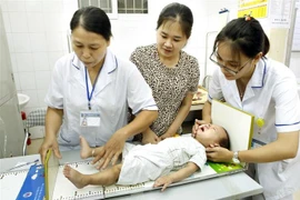 Một điểm cân, đo và cho trẻ uống Vitammin A. (Ảnh: Dương Ngọc/TTXVN)