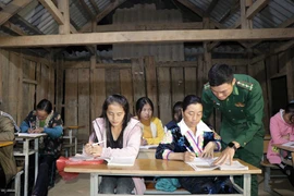 Trung úy Vì Văn Liêm, cán bộ Đồn biên phòng Mường Lạn, hướng dẫn cho các học viên tại lớp học xóa mù. (Ảnh: Hữu Quyết/TTXVN)
