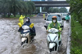 Các phương tiện đi lại khó khăn trong điều kiện ngập lụt do mua lớn. (Ảnh: Hoàng Hiếu/TTXVN)