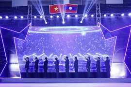 Lãnh đạo các bộ ngành liên quan của hai nước và Đại sứ Việt Nam tại Lào Nguyễn Bá Hùng nhấn nút khai mạc Hội chợ thông qua ứng dụng tương tác trên màn hình LED. (Ảnh: Phạm Kiên/TTXVN)