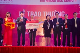 Khách hàng Lê Thị Thơi nhận sổ tiết kiệm 1 tỷ đồng giải đặc biệt từ lãnh đạo Agribank. (Nguồn: Agribank)