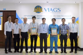 Anh Đường Khánh Tùng (thứ tư từ trái sang) và anh Trần Ngọc Kỳ (thứ ba từ phải sang) nhận thư biểu dương của Ban lãnh đạo Công ty Dịch vụ mặt đất sân bay Việt Nam. (Ảnh: CTV/Vietnam+)