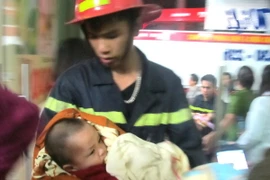 Cảnh sát chữa cháy cứu cháu bé khỏi nơi xảy ra cháy. (Ảnh: Doãn Tấn/TTXVN)