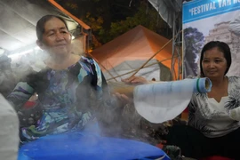 Các nghệ nhân biểu diễn công đoạn tráng bánh tại lễ hội. (Ảnh: Thanh Tân/TTXVN)