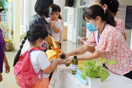 Giáo viên Trường Mầm non Tuổi thơ (Quận 8) hướng dẫn trẻ rửa tay trước khi vào lớp. (Ảnh: Thu Hoài/TTXVN)