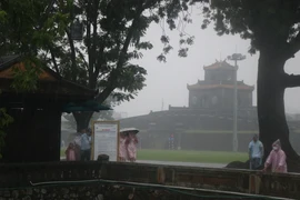 Du khách thích thú khám phá Huế trong mưa. (Ảnh: Đỗ Trưởng/TTXVN)