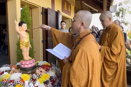 Thượng Tọa Thích Tâm Huy, Trụ trì Trúc Lâm Thiền viện thực hiện nghi lễ tắm Phật. (Ảnh: Thu Hà/TTXVN)