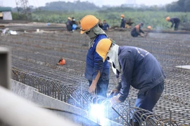 Các công nhân vẫn tiếp tục thi công và đón Tết Dương lịch 2022 ngay trên công trường Cầu Vĩnh Tuy 2. (Ảnh: Hoàng Hiếu/TTXVN) 