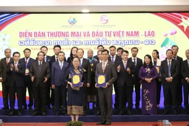 Nghi thức trao biên bản ghi nhớ hợp tác và hợp đồng kinh tế giữa các doanh nghiệp Việt Nam-Lào tại diễn đàn. (Ảnh: Xuân Anh/TTXVN)