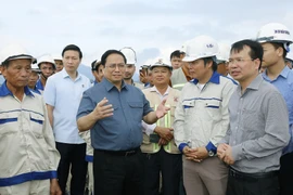 Thủ tướng Phạm Minh Chính nói chuyện với công nhân xây dựng dự án tuyến đường Đông-Tây giai đoạn 1 đoạn từ thành phố Tam Điệp đến huyện Nho Quan. (Ảnh: Dương Giang/TTXVN) 