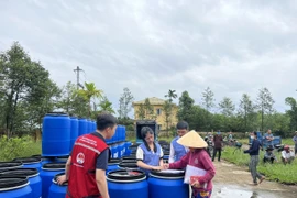 Hỗ trợ thùng nhựa cho các gia đình có nguy cơ chịu ngập lụt do mưa bão ở Thừa Thiên-Huế. (Ảnh: TTXVN phát)