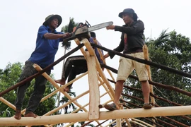 Người dân làng Bờ Reo chung tay dựng lại nhà bị sập cho người dân sau bão. (Ảnh: Phạm Cường/TTXVN) 