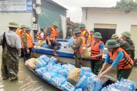 Lực lượng chức năng vận chuyển nước uống hỗ trợ người dân vùng bị ngập tại huyện Quỳnh Lưu (Nghệ An). (Ảnh: Tá Chuyên/TTXVN) 