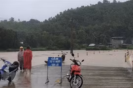 Lực lượng chức năng huyện Đồng Xuân, tỉnh Phú Yên gắn biển cảnh báo và cử lực lượng chức năng chốt chặn tại một tuyến đường bị ngập trong nước lũ. (Ảnh: TTXVN phát)