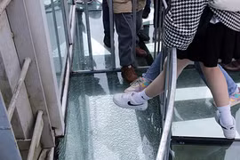 Khu vực miếng kính được cho là chủ đầu tư cố tình làm nứt, vỡ đã được khoanh vùng bảo vệ và luôn có nhân viên túc trực để giới thiệu, nhiều du khách vẫn muốn đặt chân để trải nghiệm. (Ảnh: Quý Trung/TTXVN)