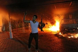 Một người đàn ông Libya giương khẩu súng trường bên ngoài căn nhà và xe cộ của lãnh sự quán Mỹ vào đêm 11/9. (Ảnh: AFP)