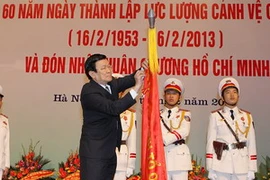 Chủ tịch nước Trương Tấn Sang gắn Huân chương Hồ Chí Minh lên Cờ truyền thống của Lực lượng Cảnh vệ Công an nhân dân. (Ảnh: Nguyễn Khang/TTXVN)