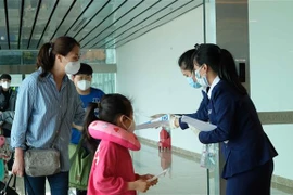 Nhân viên Sân bay quốc tế Cam Ranh phát tờ rơi hướng dẫn phòng dich COVID-19 cho hành khách tại khu vực nhập cảnh. (Ảnh: Nguyễn Dũng/TTXVN)