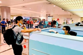 Cán bộ công an cửa khẩu Tân Sơn Nhất chủ động trang bị đầy đủ khẩu trang, găng tay trong khi làm nhiệm vụ. (Ảnh: Thành Chung/TTXVN)