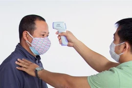 Kiểm tra thân nhiệt hành khách từ Hà Nội đến Phú Yên. (Ảnh: Xuân Triệu/TTXVN)