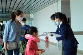 Nhân viên Sân bay quốc tế Cam Ranh phát tờ rơi hướng dẫn phòng dich COVID-19 cho hành khách tại khu vực nhập cảnh. (Ảnh: Nguyễn Dũng/TTXVN)