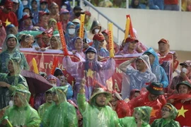 Cổ động viên Việt Nam đội mưa cổ vũ cho các cầu thủ đội U23 Việt Nam. (Ảnh: Minh Quyết/TTXVN)