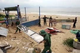 Cán bộ, chiến sỹ biên phòng đồn Phú Lộc, quận Thanh Khê, thành phố Đà Nẵng giúp dân tháo gỡ, di dời tài sản trên bãi biển vào sâu đất liền tránh bão số 4. (Ảnh: Trần Lê Lâm/TTXVN)
