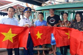 Tặng cờ Tổ quốc cho bà con ngư dân huyện Cát Hải. (Ảnh: Minh Huệ/TTXVN)