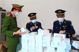 Kiểm đếm số bộ xét nghiệm nhanh COVID-19 trong một vụ vi phạm. (Ảnh minh họa: TTXVN phát)