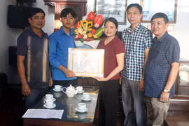 Lãnh đạo Ủy ban Nhân dân huyện Hải Hậu trao Giấy khen cho em Bùi Hải An (thứ 2, từ trái sang). (Ảnh: TTXVN phát)