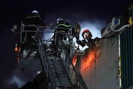 Đến 20h30 ngày 1/8, lực lượng cảnh sát phòng cháy, chữa cháy vẫn tiếp tục sử dụng thang cứu hộ xử lý đám cháy. (Ảnh: Phạm Kiên/TTXVN)