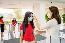 Đo thân nhiệt cho học sinh trước khi vào trường học. (Nguồn: TTXVN)
