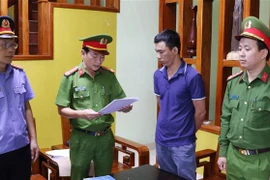 Lực lượng chức năng đọc quyết định khởi tố đối với bị can Đỗ Khắc Điệp. (Ảnh: TTXVN phát)