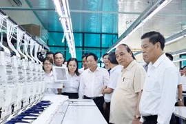 Chủ tịch nước Nguyễn Xuân Phúc thăm các phân xưởng sản xuất tại Công ty trách nhiệm hữu hạn thương mại Sao Mai. (Ảnh: Thống Nhất/TTXVN)