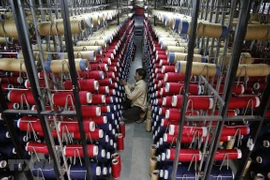 Công nhân kiểm tra các ống sợi trên máy dệt thảm tại một nhà máy ở ngoại ô Jammu, Ấn Độ. (Ảnh: AFP/TTXVN)