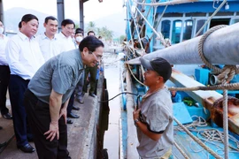 Thủ tướng Phạm Minh Chính thăm hỏi, động viên ngư dân tàu cá đang neo đậu tại cảng cá xã Cà Ná. (Ảnh: Dương Giang/TTXVN)