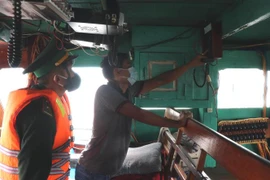 Kiểm tra thiết bị liên lạc trên tàu đánh bắt xa bờ của ngư dân. (Ảnh: Đỗ Trưởng/TTXVN)