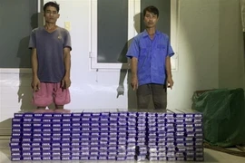 Đối tượng Nguyễn Văn Đoàn và Võ Thanh Thành bị Đồn Biên phòng Vàm Trảng Trâu bắt giữ khi vận chuyển 2.000 gói thuốc lá lậu. (Ảnh: TTXVN phát)