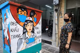 Người dân xem những bức tranh cổ động về công tác phòng chống dịch COVID-19. (Ảnh: Thành Đạt/TTXVN)