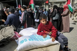 Người dân Palestine nhận hàng cứu trợ tại Dải Gaza. (Ảnh: AFP/TTXVN)