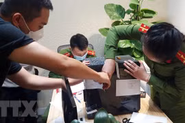 Lực lượng chức năng khám xét và niêm phong, thu giữ tài liệu tại trụ sở FLC. (Ảnh: Phạm Kiên/TTXVN)