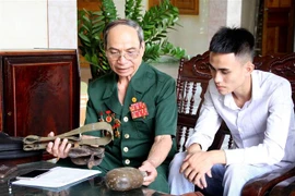 Thương binh Nguyễn Đình Duyên kể lại cho cháu nghe về những trận đánh oanh liệt của ông cùng đồng đội trong chiến tranh. (Ảnh: Văn Tý/TTXVN)