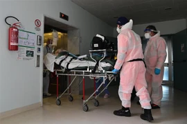 Nhân viên y tế chuyển bệnh nhân COVID-19 vào bệnh viện ở Cremona, Italy. (Ảnh: AFP/TTXVN)