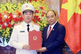 Chủ tịch nước Nguyễn Xuân Phúc trao Quyết định thăng cấp bậc hàm từ Trung tướng lên Thượng tướng đối với Thứ trưởng Bộ Công an Trần Quốc Tỏ. (Ảnh: Thống Nhất/TTXVN)